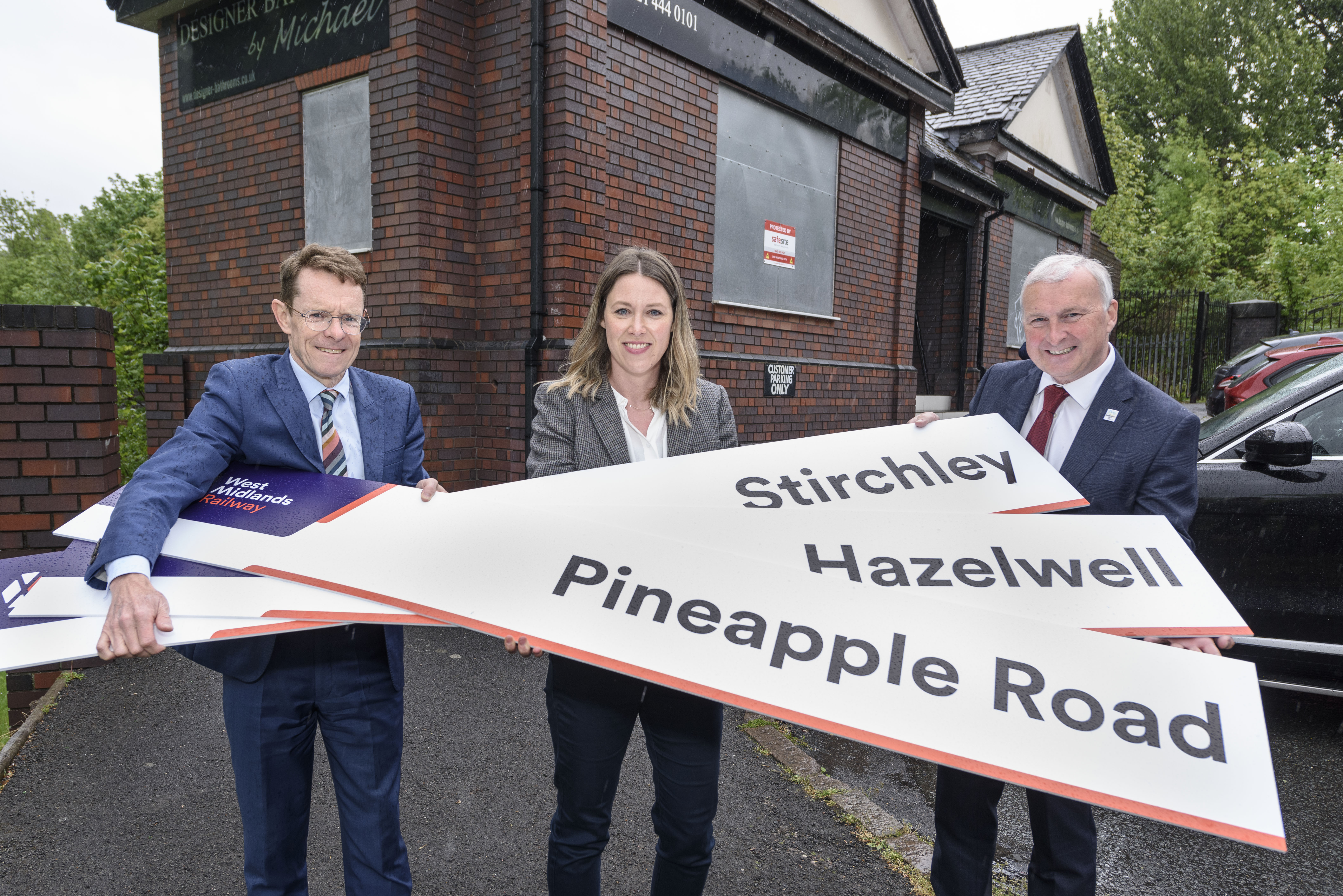 Mayor Andy Street, Kate Trevorrow and Councillor Ian Ward holding station signs for Stirchley, Hazelwell and Pineapple Road