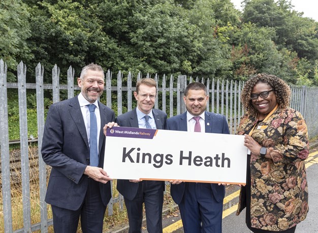 Executives in front of station sign